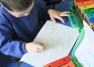 Joseph (4) is using music symbols to write his own colourful score.